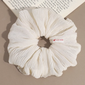 Détail d'un chouchou plissé blanc surdimensionné avec étiquette fait main cœur rouge