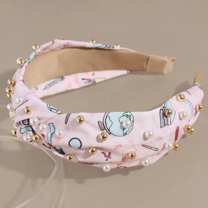 Detail eines rosa Stoffhaarbands mit Schulmotiv, Goldperlen und weißen Perlen