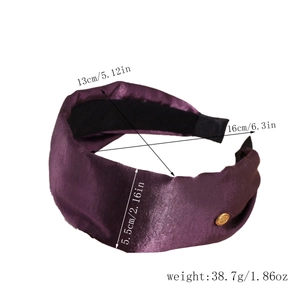 Detail view of purple satin headband with golden emblem and non-slip inner lining