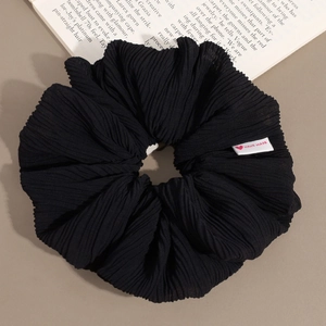 Détail d'un chouchou noir plissé avec étiquette cœur faite main et texture élégante