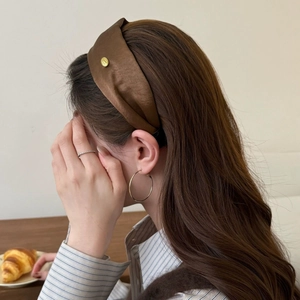 Chocolate brown satin headband with golden metal detail worn by model in minimalist setting