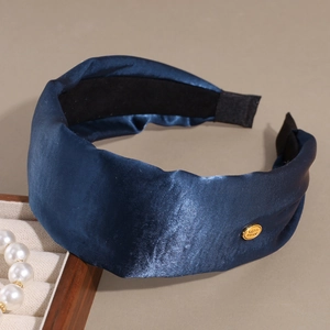 Deep blue satin headband with gold metal logo on neutral grey elegant background