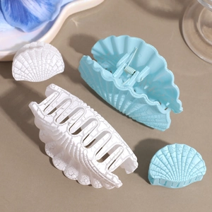 Close-up of matte shell-shaped hair claws featuring marble texture and metal spring detail