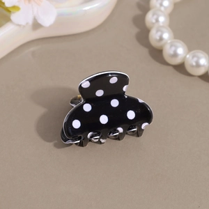 Nahaufnahme der kleinen schwarz-weißen Polka-Dot-Haarklammer auf elegantem beigen Grund