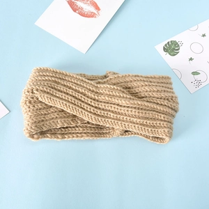 Close-up of beige knitted twist knot headband with ribbed texture on blue background