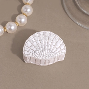 Macro shot of white shell-shaped hair claw with retro crackle texture detail