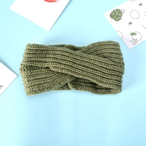 Olive green knitted twisted headband in thick wool style on a light blue artistic background