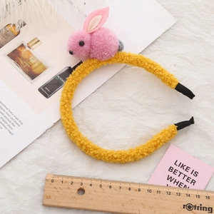 Vue détaillée du serre-tête en peluche dorée avec oreilles de lapin roses et règle