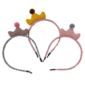 Détail de trois serre-têtes couronne de princesse tricotés avec pompons pour filles