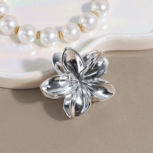 Dettaglio di una pinza per capelli a fiore in metallo argento con finitura lucida