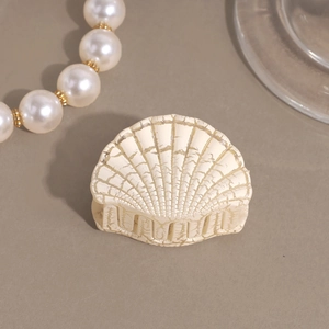 Detailed macro view of shell-shaped hair claw with cream finish and vintage cracked texture