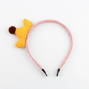 Détail d'un serre-tête en tissu rose avec couronne tricotée jaune et petite boule peluche