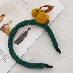 Vue détaillée d'un serre-tête en peluche verte avec un lapin jaune sur fond de tissu doux