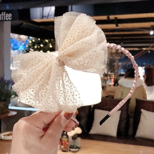 Détail du bandeau en soie rose avec grand nœud en tulle beige et paillettes dorées