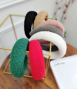 Dettaglio di fasce per capelli in pile peluche in vari colori su supporto dorato