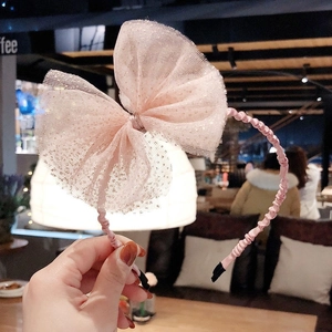 Détail du serre-tête rose avec nœud en maille à pois et cadre enveloppé de satin
