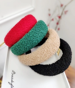 Dettaglio di cerchietti in peluche nei colori rosso, verde, beige e nero su un vassoio