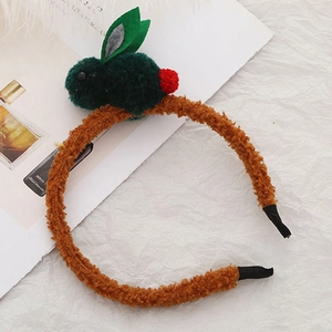Gros plan d'un serre-tête en peluche marron orné d'un lapin vert et d'un pompon rouge