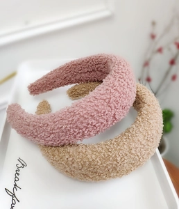Dettaglio di cerchietti in spugna felpata rosa e cammello con calda trama invernale