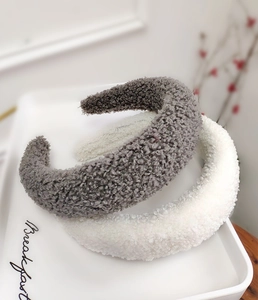 Dettaglio di cerchietti larghi in peluche grigio e bianco su un vassoio