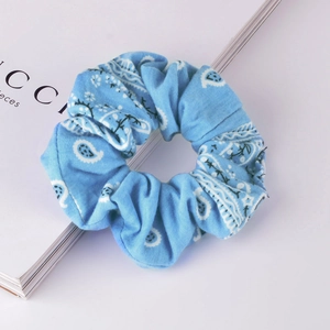 Close-up of light blue paisley print scrunchie on a white minimalist background