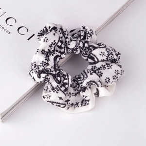 Close-up of black and white paisley floral scrunchie with soft pleated fabric texture