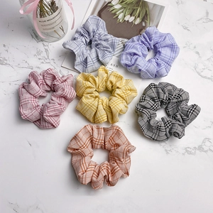 Set mit 6 bunten karierten Baumwoll-Haargummis in Pastelltönen auf weißem Marmor