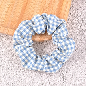 Blue gingham checkered scrunchie on wooden tray, stylish minimalist fabric hair tie accessory