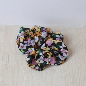 Detailaufnahme von Blumen-Chiffon-Haargummi mit bunten Mustern auf Holzuntergrund