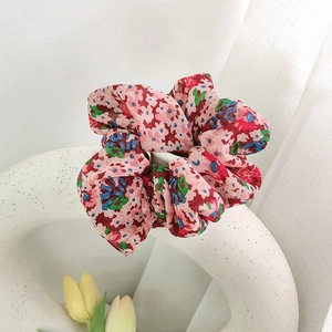 Detailansicht eines Scrunchie mit Blumenmuster in Rosa und Rosé auf einer weißen Vase