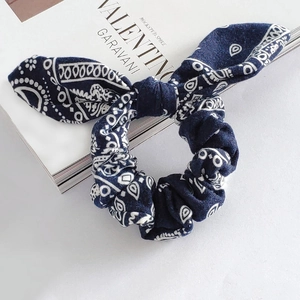 Detail of a dark blue paisley bunny ear scrunchie on a magazine for a stylish look