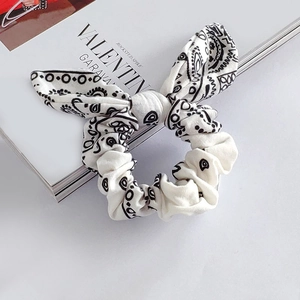 Detail of white paisley rabbit ear scrunchie with elastic fabric on a fashion magazine