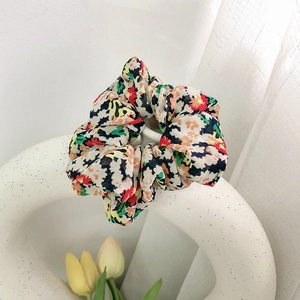 Nahaufnahme eines floralen Haargummis mit bunten Mustern auf einer minimalistischen Vase