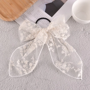 Close-up of elegant white floral lace bow hair tie with embroidery detail and elastic band