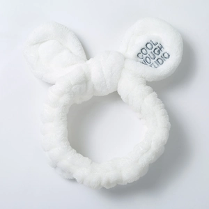 Close-up of white plush bunny ear headband with grey embroidery on soft coral fleece