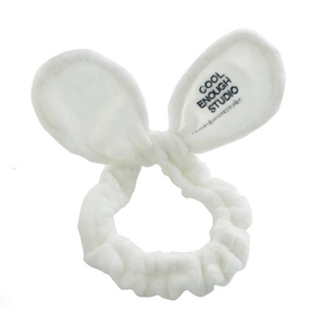 Detail of soft white plush rabbit ear headband with embroidered brand text