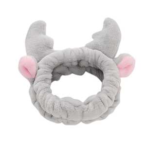 Macro shot of grey flannel headband with plush cow horns and pink ears for skincare