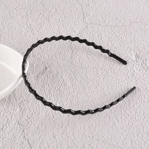 Détail du serre-tête ondulé en plastique noir brillant avec dents antidérapantes de fixation