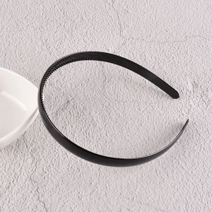 Détail d'un serre-tête en plastique noir avec dents antidérapantes sur fond de pierre