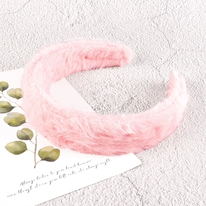 Close-up of soft pink plush headband with fluffy texture on a minimalist background