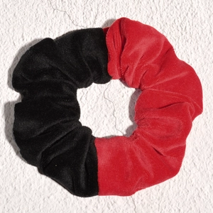 Detailed view of bicolor red and black velvet scrunchie with soft pleated texture