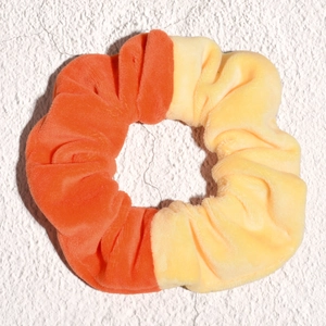 Close-up of contrast color velvet scrunchie featuring orange and yellow plush fabric