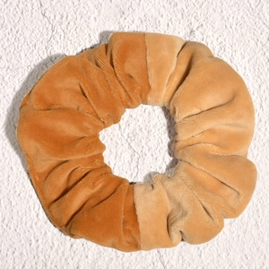 Detail of velvet scrunchie in caramel and apricot color combination with soft texture