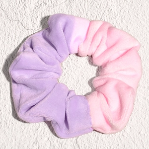Detailed macro of a soft velvet scrunchie showing the purple gradient color and fabric texture