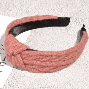 Detail of pink knitted headband featuring a top knot and chunky braided texture