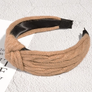 Macro view of brown cable-knit headband with twist knot design and soft satin lining