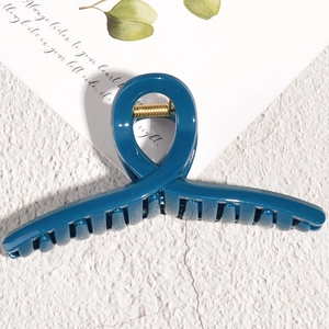Deep blue hair claw clip with cross design and golden metal spring on minimalist background