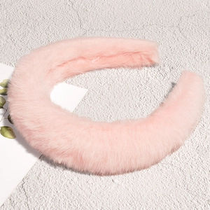 Gros plan d'un serre-tête en peluche rose clair doux avec une texture moelleuse sur pierre