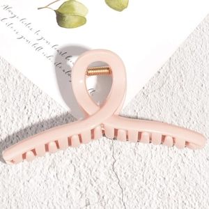 Detail of soft pink hair claw clip with crossed structure and gold spring component