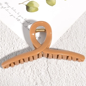 Detail of glossy beige hair claw clip with golden metal spring on minimalist background